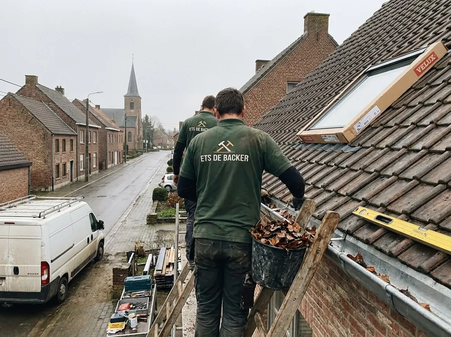 Dakwerkers van Ets De Backer ruimen de dakgoot op na de werken